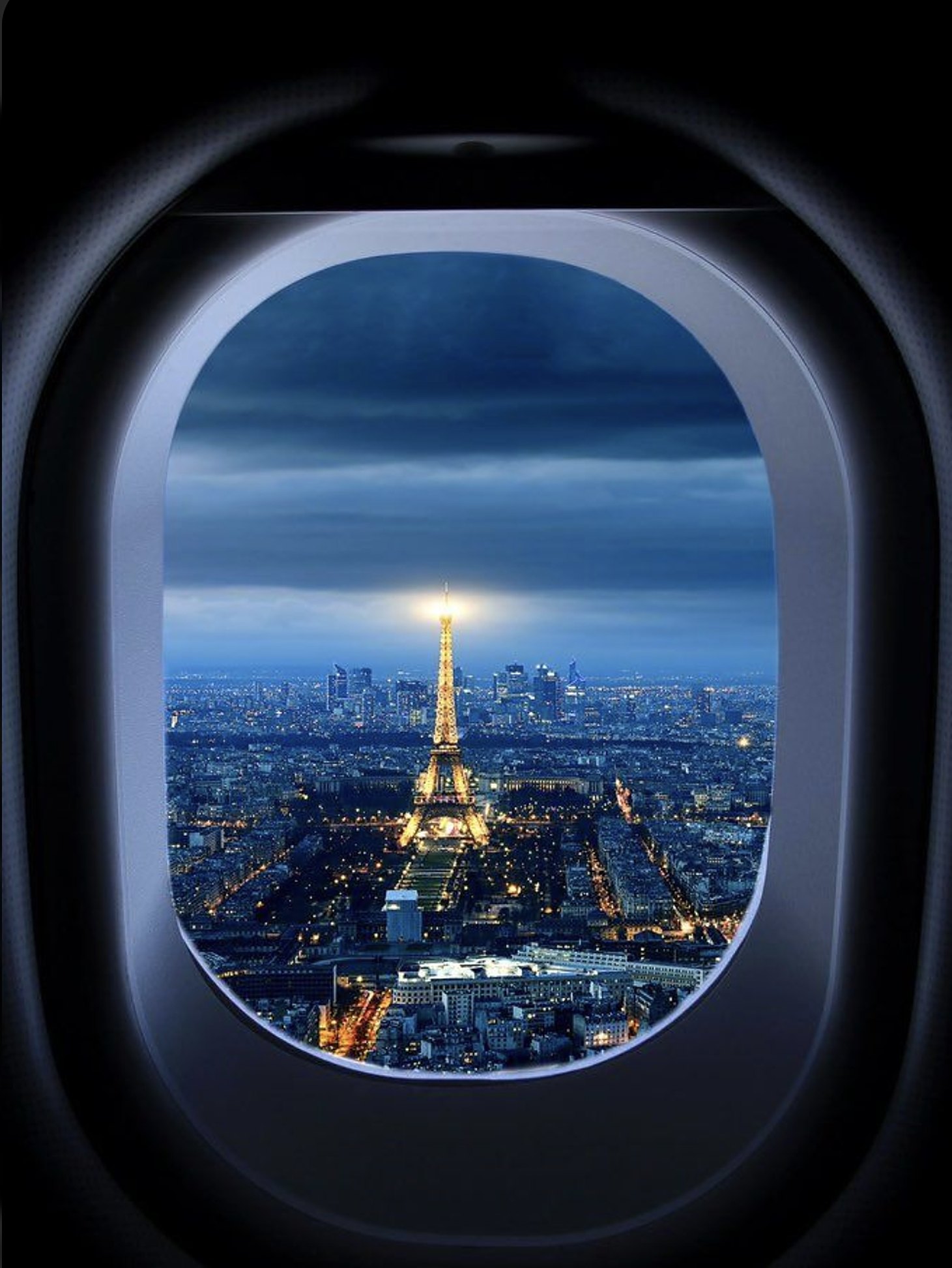 Paris at night seen through a private jet window